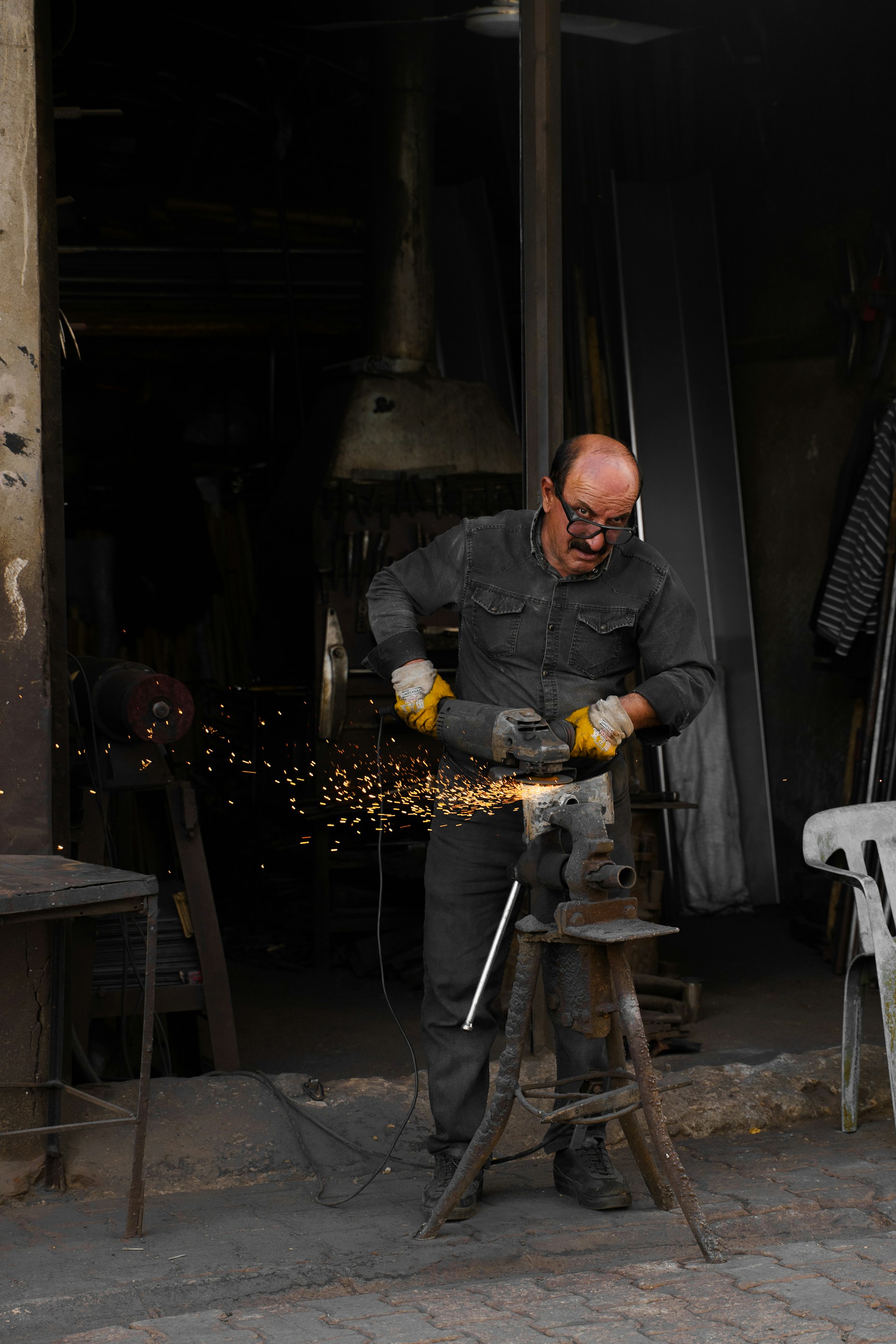 A metalworker shaping metal in a workshop, with visible sparks
